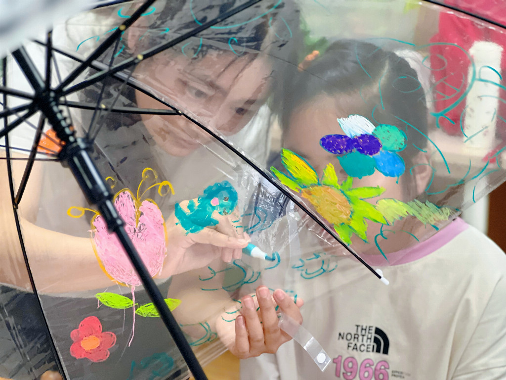图为团队成员孙雅琪和小朋友一起绘制雨伞。芮雪婷 供图.jpg